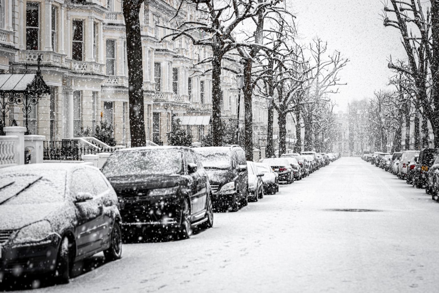 image of a London street with parked cars covered in snow